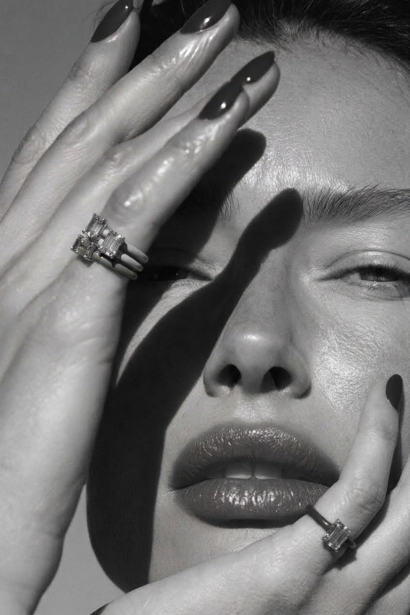 Hands wearing emerald-cut rings framing a face in black and white