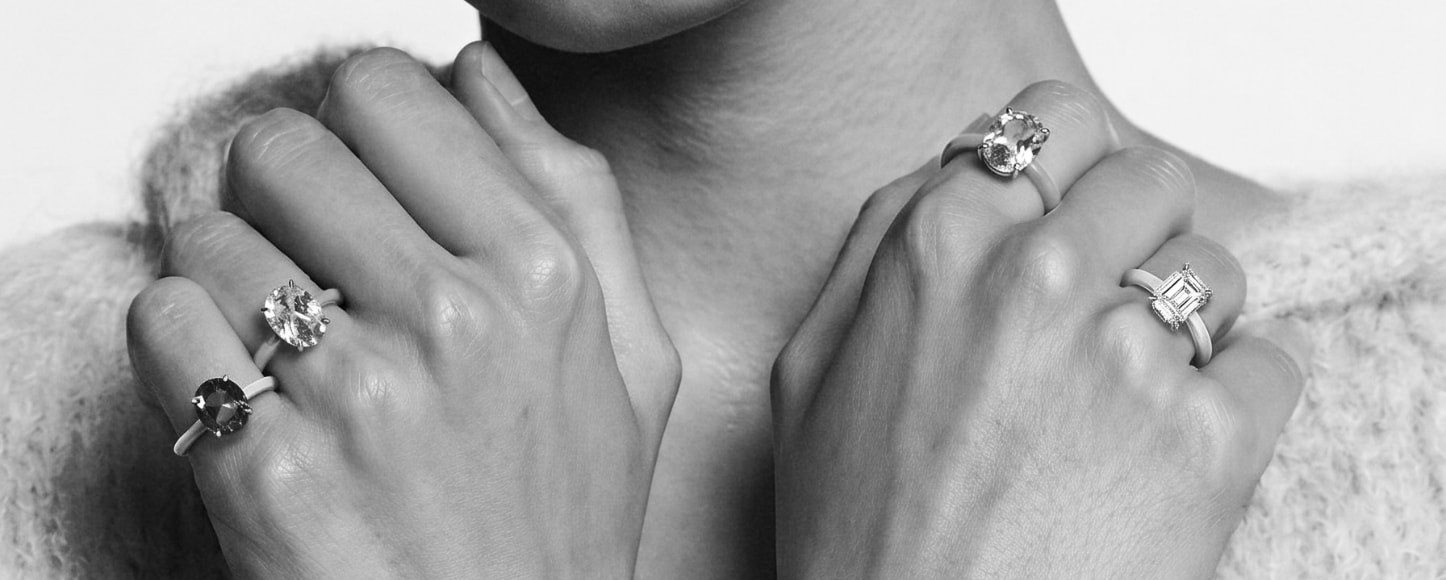 Hands wearing gemstone rings in a chunky knit sweater in black and white