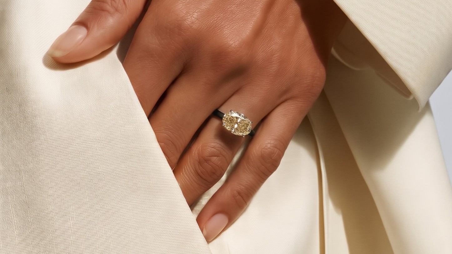 Hand with a butter-yellow stone ring tucked in a cream blazer pocket